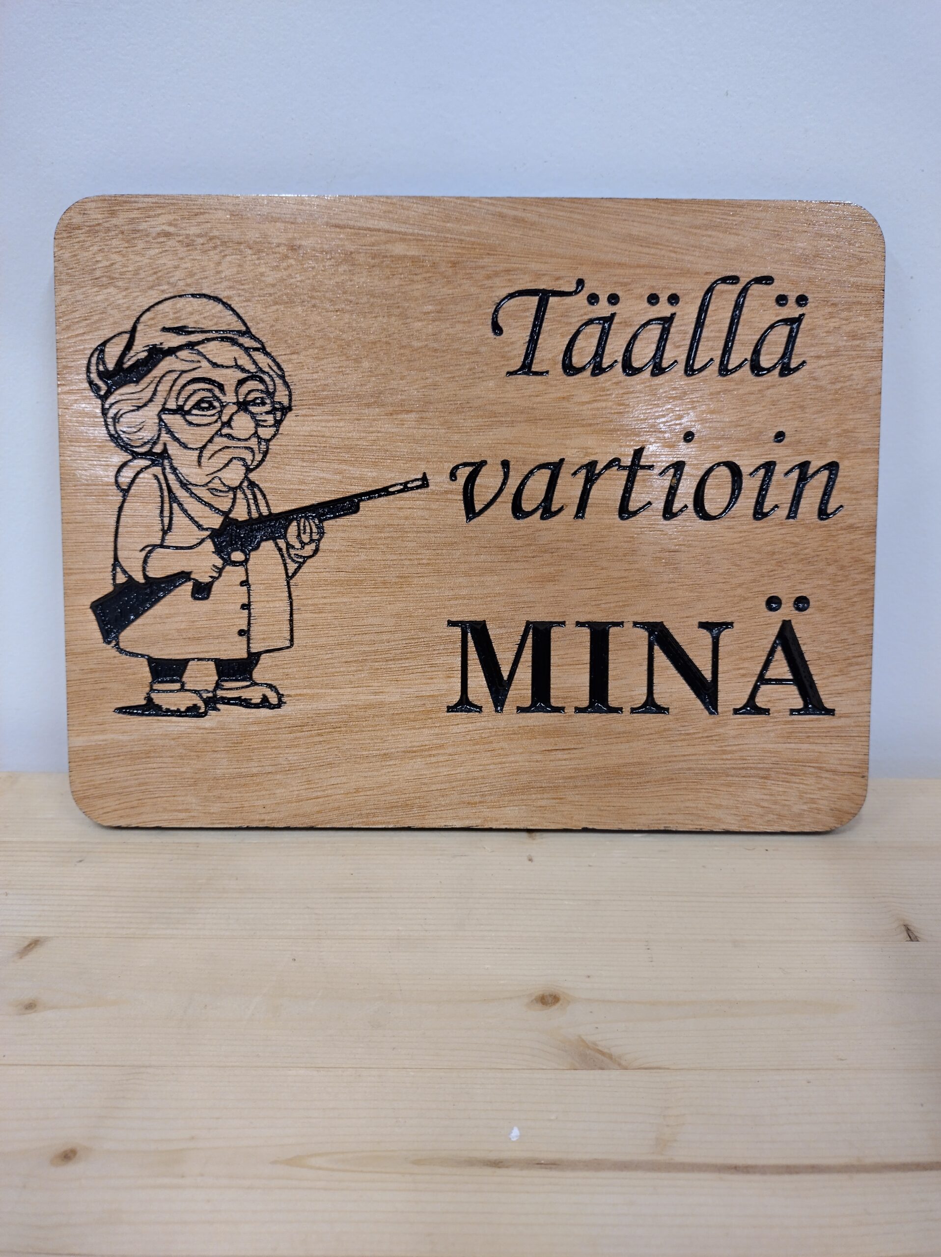 Täällä vartioin minä -kyltti mummon kuvalla